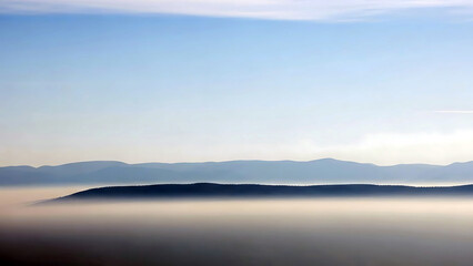 Fototapeta premium Serene mountainous landscape with layers of hills and fog under a clear blue sky at dawn or dusk moment