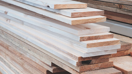 A stack of wooden planks, some of which are brown. The stack consists of planks of varying sizes in...