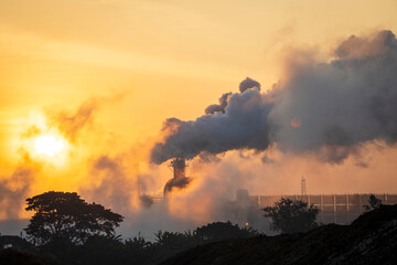 Smoke emissions from chimneys and industrial waste contributing to air pollution at sunrise, which pollutes environment and destroys the ecosystem.