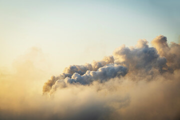 Smoke moving up polluting atmosphere during sunrise. Smoke from industrial chimneys, environmental problems, air pollution.