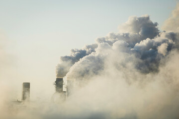 Smoke from industrial chimneys in the sky, air pollution from power plant chimneys, global warming, environmental problems.