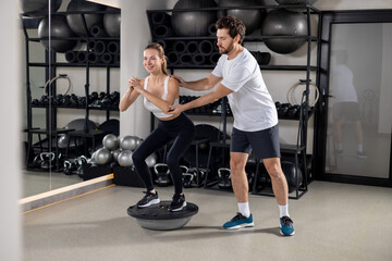 Blonde young woman exercising in the gym with a coach