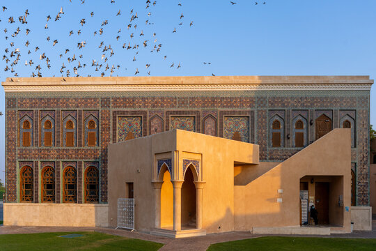 Doha, Qatar - 05 November 2025: View of birds soaring above the intricately designed building with beige walls, ornate windows, and shadows casting a serene glow.