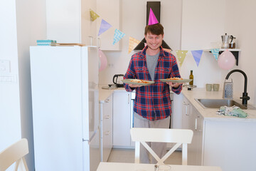 Young man celebrates his birthday at home, surrounded by a cozy and festive setting. He enjoys his special day with cake, candles, and decorations, creating memories in a warm, cheerful atmosphere.