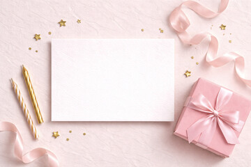 Blank white card mockup on pink background with gift box, ribbon, candles and golden stars. Feminine celebration flat lay perfect for birthday, Valentine’s Day, wedding or invitation template.