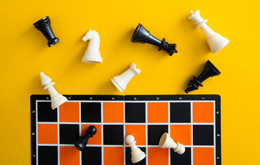 Chess pieces falling on orange board against yellow background © chee siong teh