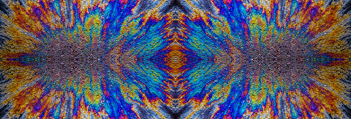 a photograph of an oil or petrol stain on a wet asphalt or pavement surface, a phenomenon called iridescence. interference of light waves reflecting off the different layers of the thin oil film