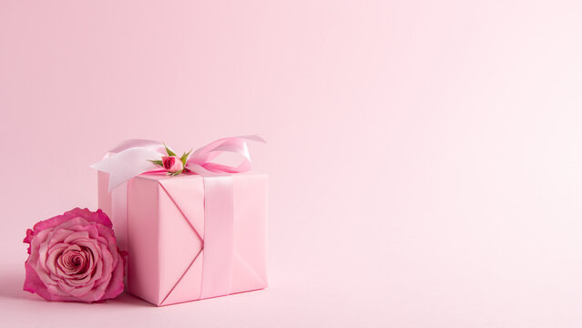 Gift, present box decorated with pink ribbon bow, rose flowers on pink background. Valentine's day, 14 February, birthday, 8 march women's day gift. Love and romance. Spring.