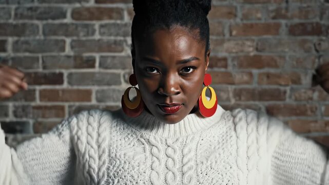 Woman in white sweater posing against brick wall