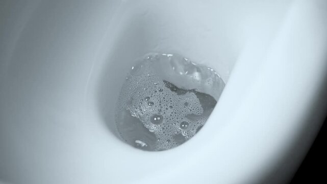 Water flowing in a clean white toilet bowl. Slow motion