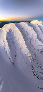 Aerial view of snow-covered mountain peaks kissed by the soft glow of the rising sun, Piz Palu, Pontresina, Grisons, Switzerland.