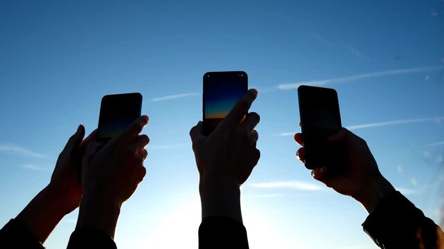 Hands holding smartphones against sky