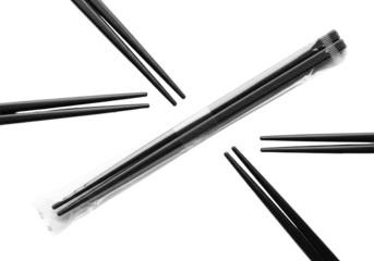 extreme close-up of three overlapping matte black disposable plastic chopsticks on a diagonal line, one wrapped, against a high-key white background. concept of disposable dining utility