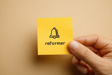 A hand holds a sticky note with a bell icon and the word "reformer" on a beige background
