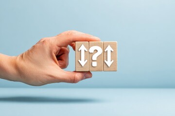 Hand holding wooden blocks, question mark flanked by arrows, against a plain blue backdrop