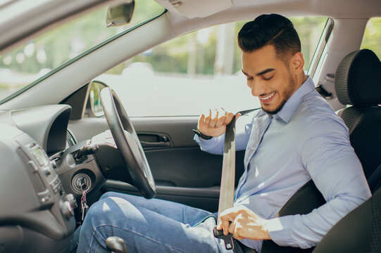 Positive arab guy in formal outfit fastening automobile seatbelt, handsome middle-eastern man entrepreneur driving nice car, going to office, sde view, copy space. Safety driving concept