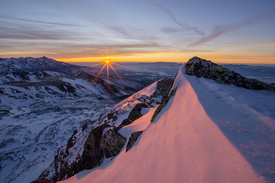 View of the sun rising over snow-covered peaks, casting a golden glow on the landscape, with shadows dancing across the terrain, Nizna Bystra, Slovakia.