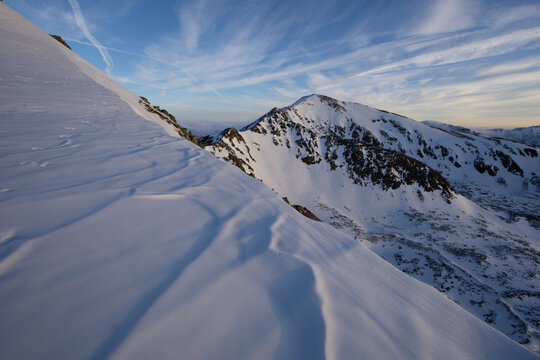 View of snow-covered mountain peaks bask in the glow of the sun, casting shadows on the pristine white landscape, Nizna Bystra, Zilina Region, Slovakia.