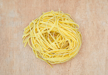 Nest of dry tagliatelle pasta on wood