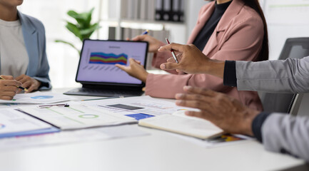 Business team analyzing financial data on tablet and paperwork during office meeting.