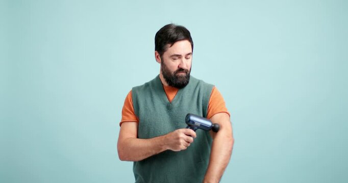 Bearded man using percussion massage gun on his arm