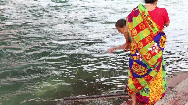 Two senior women perform a holy bath in the Ganga River at Haridwar, marking the spiritual beginning of their Char Dham Yatra with faith, devotion, and ritual cleansing.