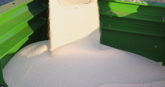 Pouring mineral fertilizer in granules into the fertilizer spreader, slow motion. Proper growth and development of plants requires a balance of nutrients found in the soil