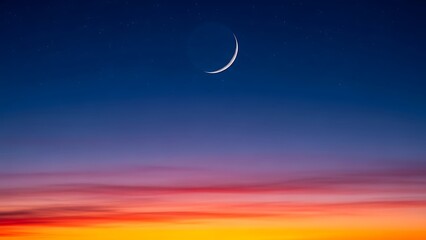Vibrant twilight sky with a delicate crescent moon and distant stars at dusk or dawn