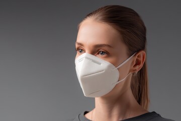 Neutral studio portrait of a masked adult looking to the right at a 45-degree angle with a white N95 mask