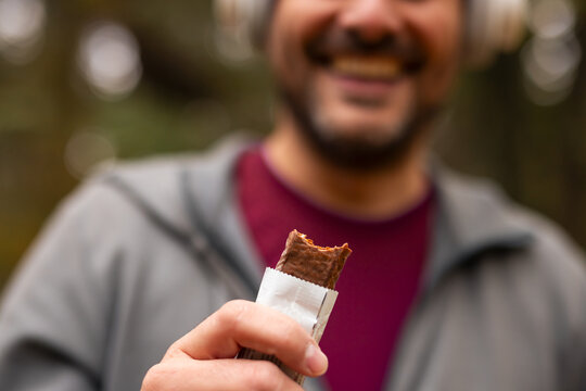 Smiling man holding a protein bar after workout