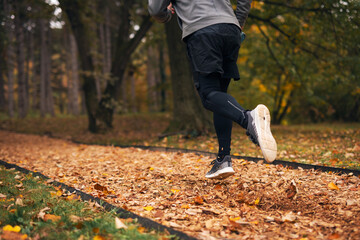 Fototapeta premium Person running on autumn trail in park during fitness workout