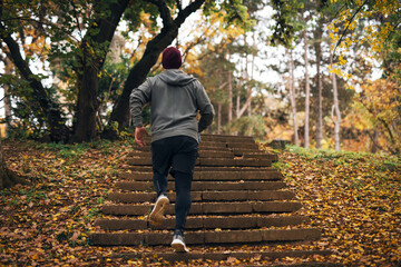 Man running up outdoor stairs in autumn park