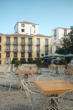 Empty outdoor cafe tables in charming European square with buildings.