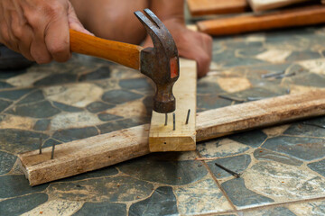 a worker removing nail on wood beam using with a claw hammer, in a workshop environment