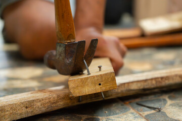 a worker removing nail on wood beam using with a claw hammer, in a workshop environment