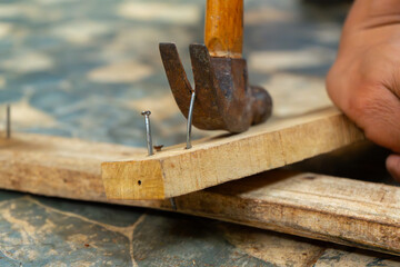 a worker removing nail on wood beam using with a claw hammer, in a workshop environment