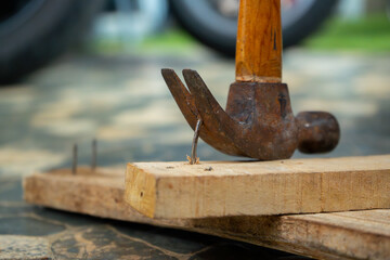 a worker removing nail on wood beam using with a claw hammer, in a workshop environment