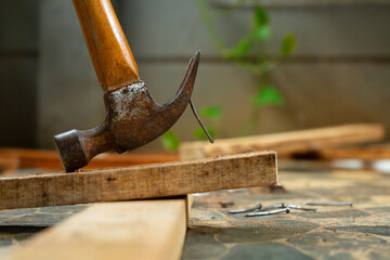 a worker removing nail on wood beam using with a claw hammer, in a workshop environment
