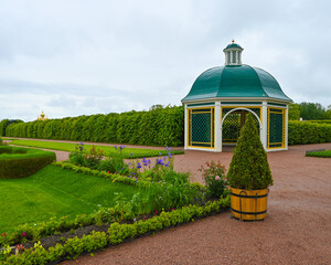 white gazebo with a green roof, which turns into a long arch for climbing plants in the form of a tunnel