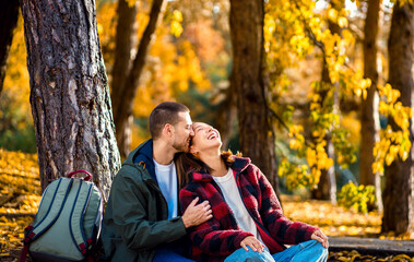 Multiracial couple sitting on grass in autumn park enjoying romantic outdoor date.