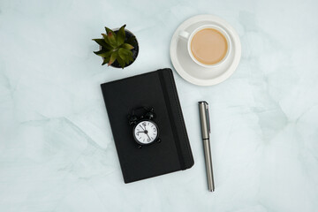 Minimal flat lay business workspace with notebook, watch, pen, coffee, and plant on marble...