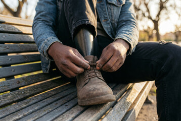 Man with prosthetic leg tying shoelaces in park