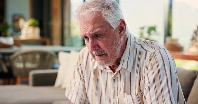Elderly, sad man and crying in mourning with regret for past mistake, loss or grief on sofa in home. Senior, male person or emotional with sadness, nostalgia or lost love for old memory or loneliness