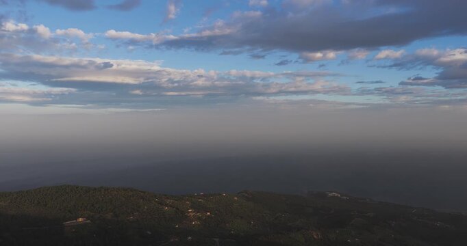 Aerial view of a hazy landscape featuring a dark mountain range and a clouded sky with contrasting light and shadow, Pollina, Sicilia, Italy.