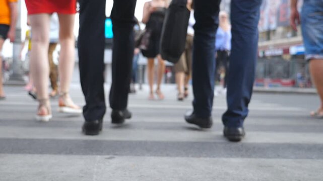 Feet of two businessmen crossing road in downtown. Legs of male coworkers walking a crosswalk in big city. Young colleagues commuting to work together. Blurred motion. Rear view Slow motion Close up
