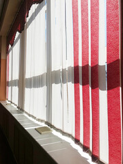 Bright interior featuring vertical blinds on large windows, allowing natural light to filter through, creating a warm and inviting atmosphere with soft shadows