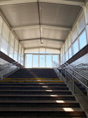 Staircase leading to bright entrance, framed by glass walls and railings, showcasing architectural design and natural light in a modern transit space