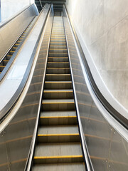 Escalator leading upwards in a modern building, showcasing sleek metallic design and smooth steps, emphasizing urban architecture and contemporary interior spaces