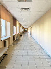 Hallway interior featuring geometric floor tiles, natural light streaming through windows, and benches along the walls, creating a spacious and inviting atmosphere with copy space