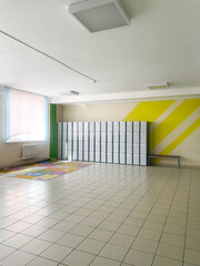 Hallway in an elementary school featuring storage lockers against a vibrant wall, showcasing a spacious environment with colorful flooring and natural light illuminating the area